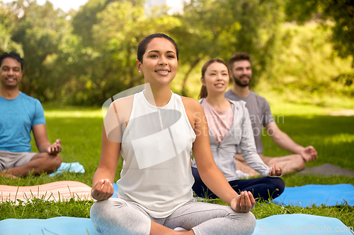 Image of group of people doing yoga at summer park