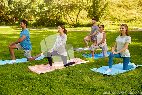 Image of group of people doing yoga at summer park