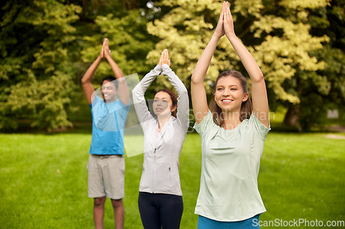 Image of group of people doing yoga at summer park