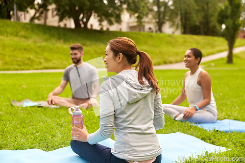 Image of group of people sitting on yoga mats at park