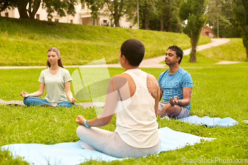 Image of group of people doing yoga at summer park