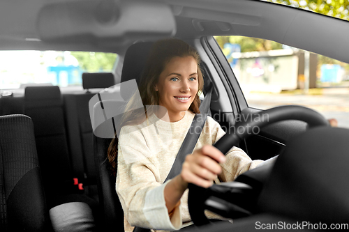 Image of smiling woman or female driver driving car in city