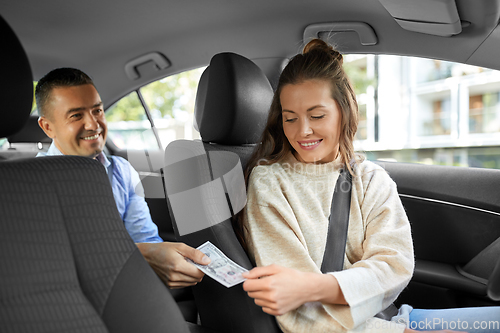 Image of female car driver taking money from passenger