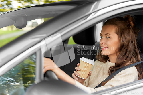 Image of woman or female driver with coffee driving car