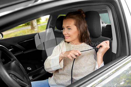 Image of woman or female driver fastening seat belt in car