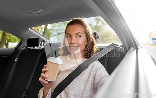 Image of smiling woman or passenger drinking coffee in car