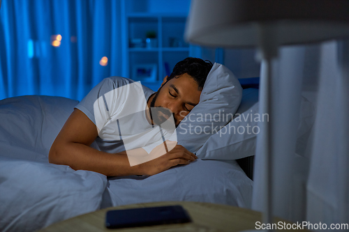 Image of indian man sleeping in bed at home at night