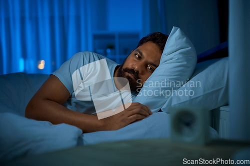 Image of sleepless indian man lying in bed at night