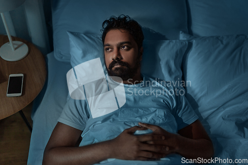 Image of speelpess indian man lying in bed at night