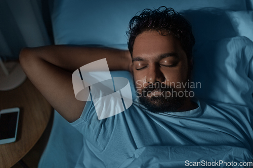 Image of indian man sleeping in bed at home at night