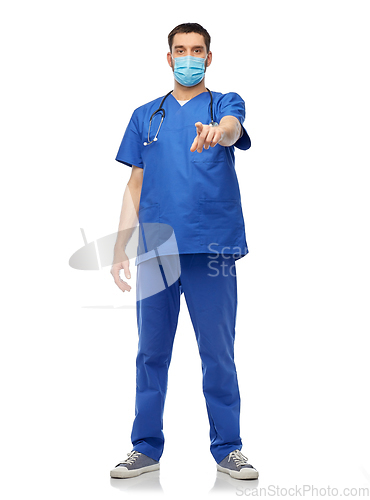 Image of male doctor in blue scrubs and mask points finger