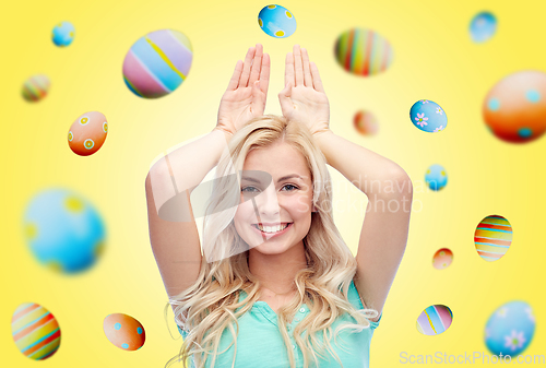 Image of happy smiling young woman making bunny ears