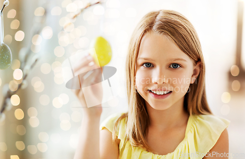 Image of girl decorating willow by easter eggs at home