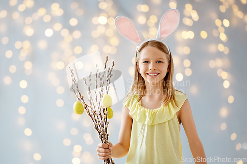 Image of smiling girl with willow decorated by easter eggs