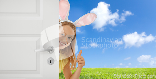 Image of happy girl with easter bunny ears peeking out door