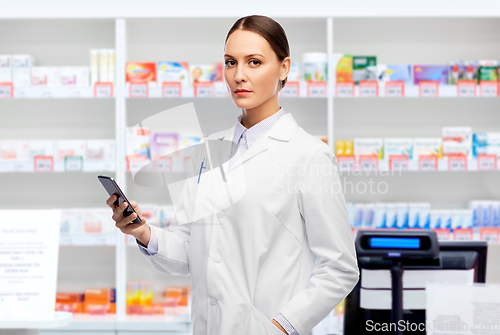Image of female doctor with smartphone at pharmacy