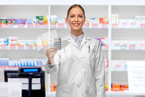 Image of smiling female doctor holding medicine at pharmacy