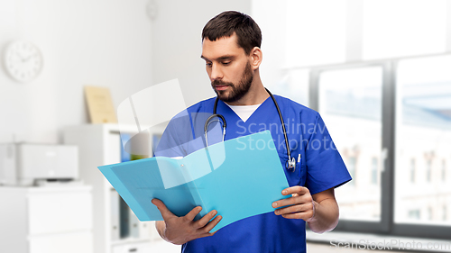 Image of male doctor reading medical report in folder