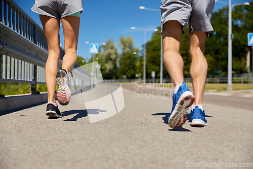 Image of feet of sporty couple running along city road