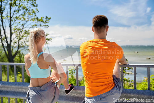 Image of young sporty couple stretching legs