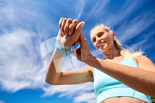 Image of smiling young woman with fitness tracker outdoors