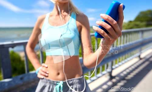 Image of sporty young woman with smartphone and earphones