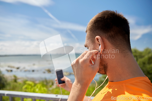 Image of young man with smartphone and earphones outdoors