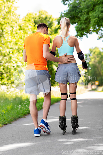 Image of happy couple with roller skates riding outdoors