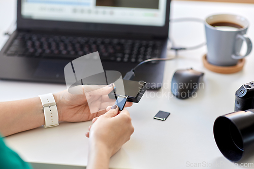 Image of woman with sd card reader and laptop at office