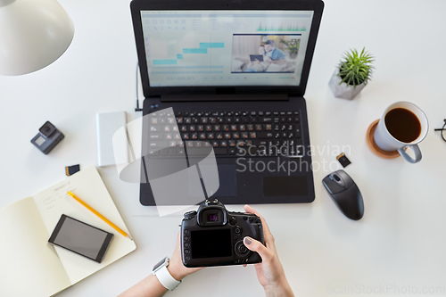Image of woman with camera and video editor on laptop