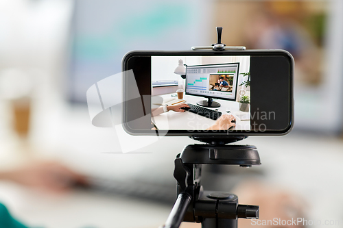 Image of smartphone recording woman working in video editor