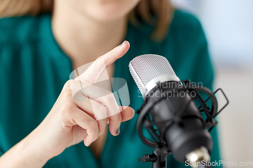 Image of woman with microphone recording podcast at studio