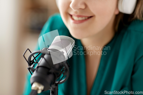 Image of woman with microphone recording podcast at studio