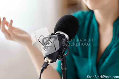 Image of woman with microphone recording podcast at studio