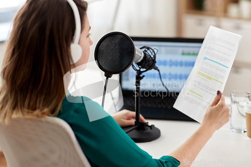 Image of woman with microphone recording podcast at studio