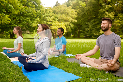 Image of group of people doing yoga at summer park