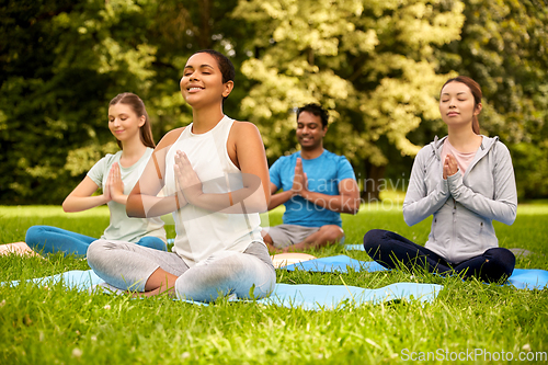 Image of group of people doing yoga at summer park