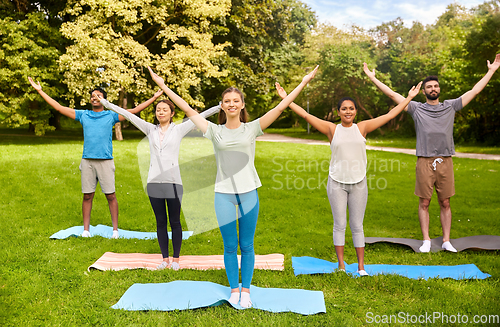 Image of group of people doing yoga at summer park