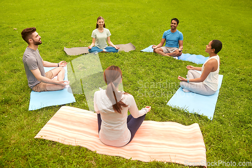 Image of group of people doing yoga at summer park