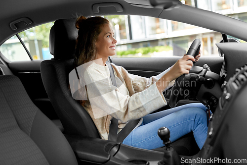 Image of smiling woman or female driver driving car in city