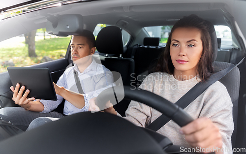Image of woman and driving school instructor in car