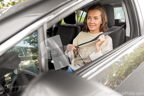 Image of woman or female driver fastening seat belt in car