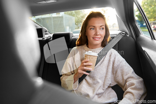 Image of smiling woman or passenger drinking coffee in car