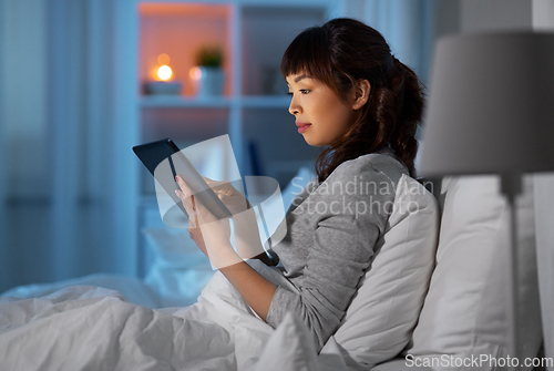 Image of asian woman with tablet pc in bed at home at night