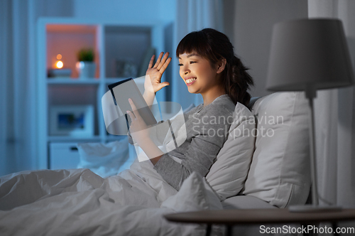 Image of woman with tablet pc in bed has video call at night