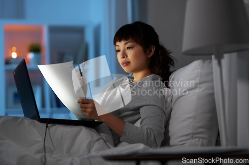 Image of woman with laptop working in bed at night