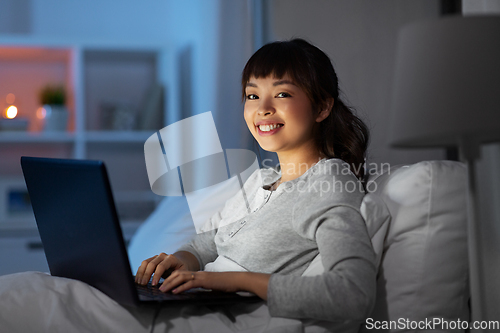 Image of woman with laptop in bed at home at night