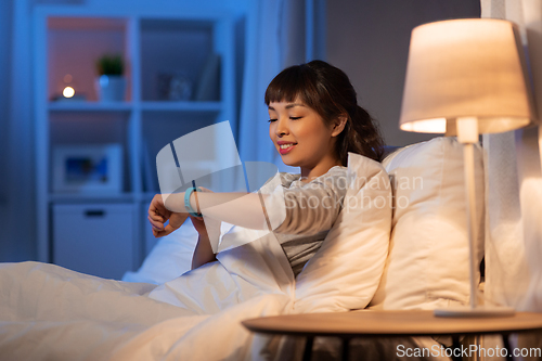 Image of asian woman with health tracker in bed at night