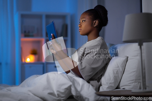 Image of woman with tablet pc in bed at home at night