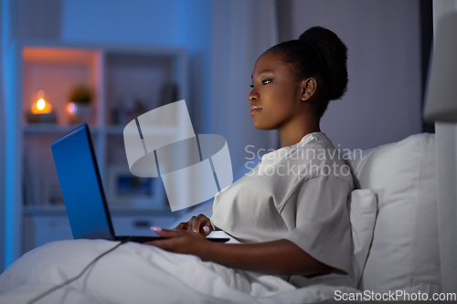 Image of woman with laptop in bed at home at night